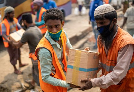 Volunteers carry high energy biscuits provided by WFP to the affected Rohingya refugees in the Kutupalong Balukhali Rohingya refugee camp on 24 March 2021. A massive fire on Monday wiped out the shelters of thousands of Rohingya refugees. As rapid assistance, WFP distributed high energy biscuits and hot meals.

The Kutupalong refugee camp in Bangladesh is one of the most densely populated refugee camps in the world. A fire broke out on Monday, 21 March, and rapidly spread across four camps in Kutupalong Balukali camp. 

Assessment results indicate that at least 11 people lost their lives and around 360 people were injured. As of 24 March, over 300 people were still missing, and more than 45,000 people displaced. At least 10,000 shelters have been damaged or destroyed as well as essential facilities including hospitals, distribution points, learning centres, women friendly services. These figures are likely to climb as assessments continue. Two WFP nutrition centres and one General Food Distribution point were burnt to the ground and two Fresh Food Corners have been destroyed. WFP was forced to also close an e-voucher outlet in Camp 9 until teams can assess the damage to the site.

WFP’s Engineering, field operations and General Food Assistance teams have been on the ground since the fire was first reported. Heavy machinery – including water bowsers, tankers and excavators – were deployed to assist in containing the blaze. 

WFP is providing rapid response food assistance in the form of high energy biscuits, in the immediate response, and hot meals. Up to 14,000 families received HEBs and around 60,000 meals are being distributed at lunch and again at dinner. WFP is also providing tens of thousands of liters of drinking water to support IOM-led distributions.

Temporary structures have been built on the sites where two WFP Nutrition centers burned down. Together with UNICEF, WFP is providing screening for malnourished children and replacing supplementary feedin